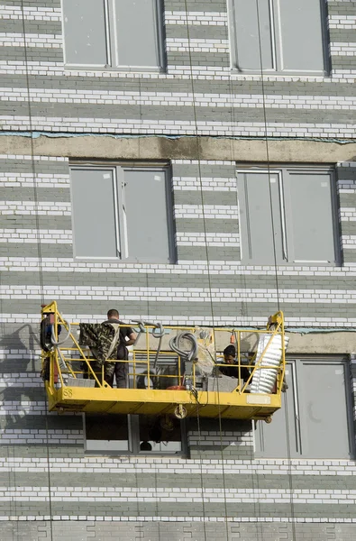 Builders in suspended platform on facade — Stock Photo, Image