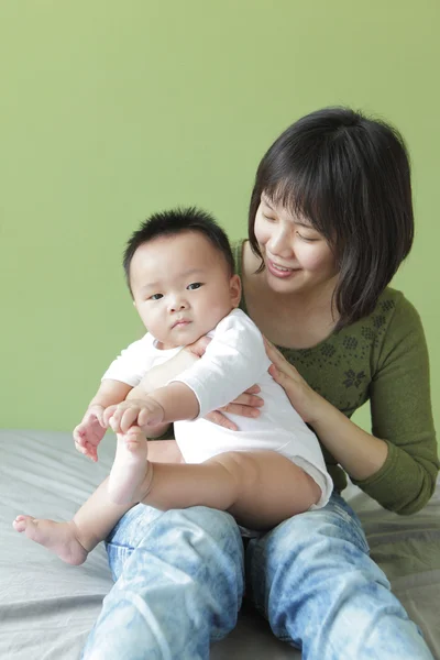 母亲和她的孩子坐在床上 — 图库照片