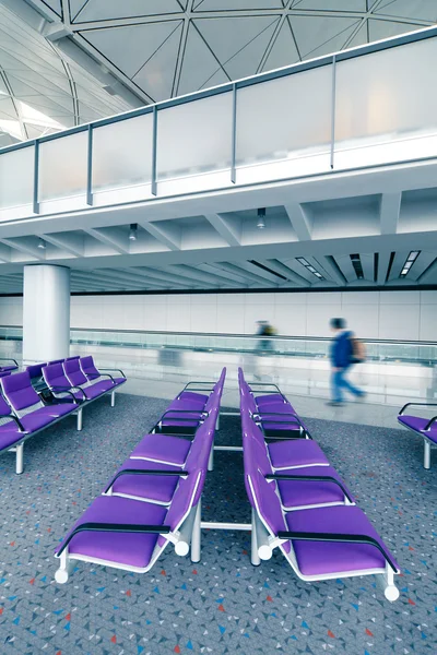 Fila de cadeira roxa no aeroporto com viajante em movimento — Fotografia de Stock