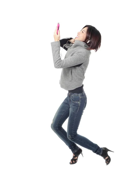 Молодая девушка счастливый прыжок и слушать музыку по мобильному телефону — стоковое фото