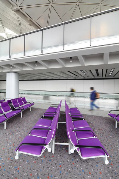 Rad av lila stol på flygplatsen med rörliga traveler — Stockfoto