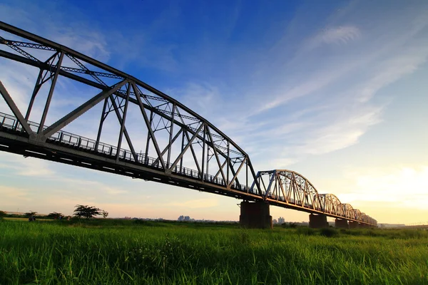 stock image Beautiful sunset with old bridge and green grass