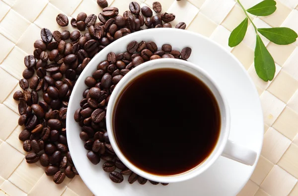 Grão de café e café quente com folha verde — Fotografia de Stock