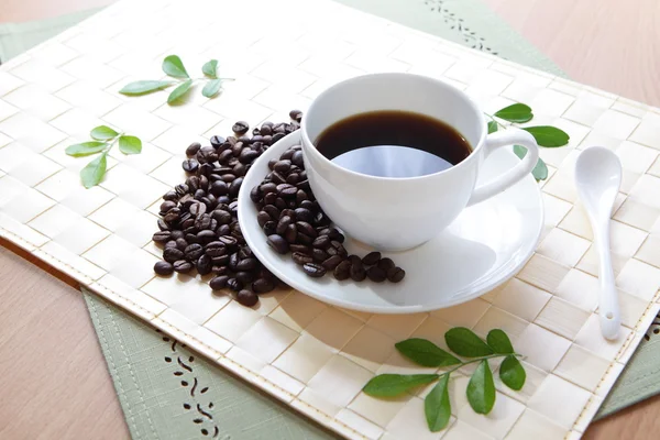 Zrnko kávy a horkou kávu s zelený list — Stock fotografie