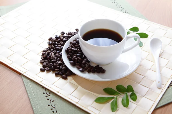 Coffee bean and hot coffee with green leaf — Stock Photo, Image