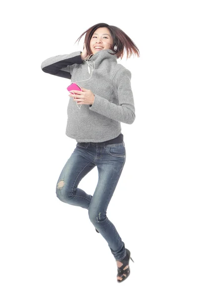 Genç kız mutlu atlamak ve cep telefonuyla müzik dinle — Stok fotoğraf