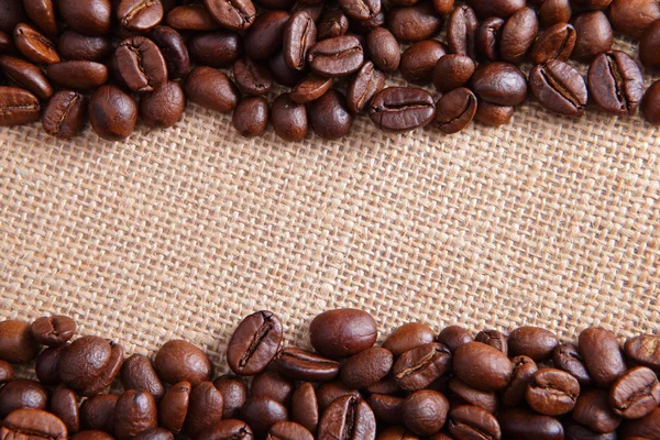 Kávová zrna na lněné pozadí — Stock fotografie