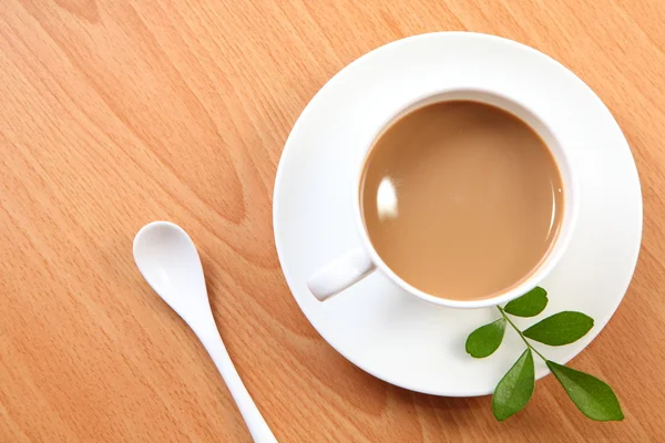 Yeşil yaprak beyaz bir fincan sütlü kahve — Stok fotoğraf