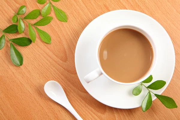 Yeşil yaprak beyaz bir fincan sütlü kahve — Stok fotoğraf
