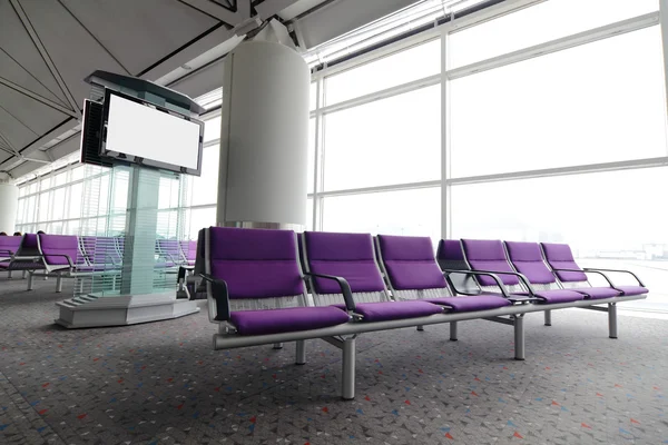 TV LCD e fileira de cadeira roxa no aeroporto — Fotografia de Stock