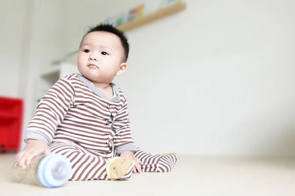 Söt baby ser vänster och ta sin nappflaska — Stockfoto