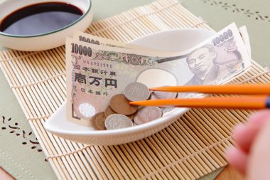 Japanese yen money in the bowl with chopsticks clipart