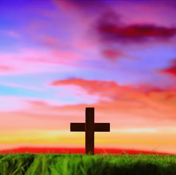 Cross silhouette on grass with sunset background — Stock Photo, Image