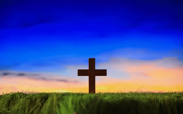 Cross silhouette on grass with sunset background — Stock Photo, Image