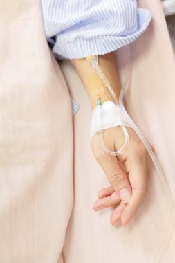 Patient's hand with an intravenous drip before surgery clipart