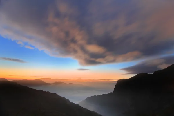 Dramatyczne chmury toczenia w górach na zachodzie słońca — Zdjęcie stockowe