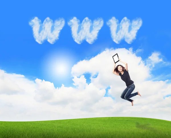 Девочка прыгает и показывает планшетный компьютер с облаком www — стоковое фото