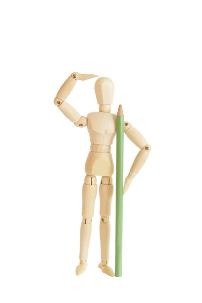 Cute wooden figure holding green pencil and looking — Stock Photo, Image