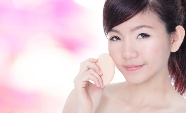 Mujer aplicando base en la cara con esponja cosmética —  Fotos de Stock