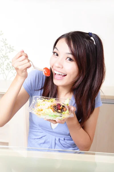 Menina feliz comer salada em casa — Fotografia de Stock