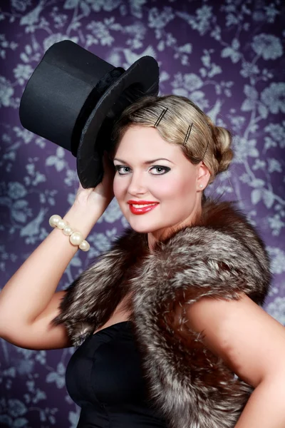 Smiling beautiful woman in fur is holding black hat — Stock Photo, Image