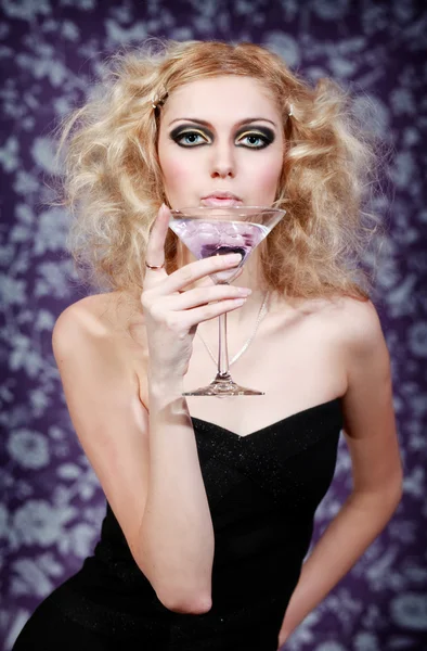 Beautiful blond young female with purple cocktail on a floral background