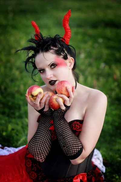 Beautiful gothic female holding apples in her hands — Stock Photo, Image