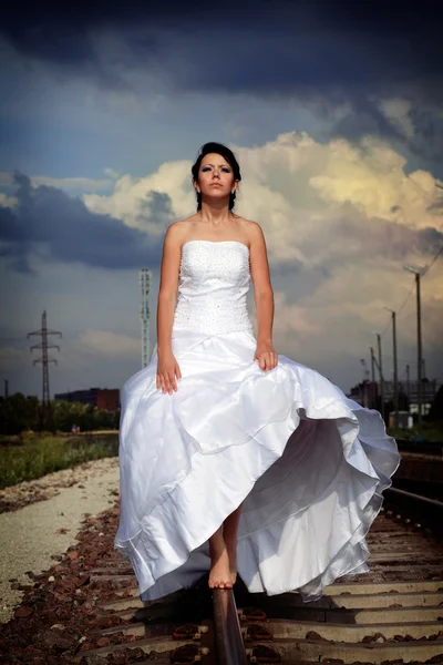 Linda jovem noiva morena está andando na estrada de ferro Fotografias De Stock Royalty-Free