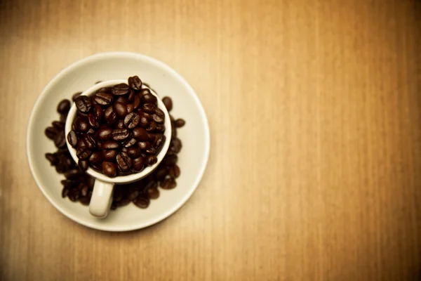 Tazza di chicchi di caffè su un tavolo di legno Fotografia Stock