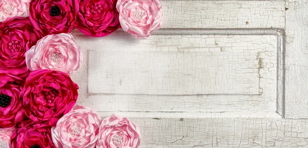 Pink vintage flowers on aged door — Stock Photo, Image