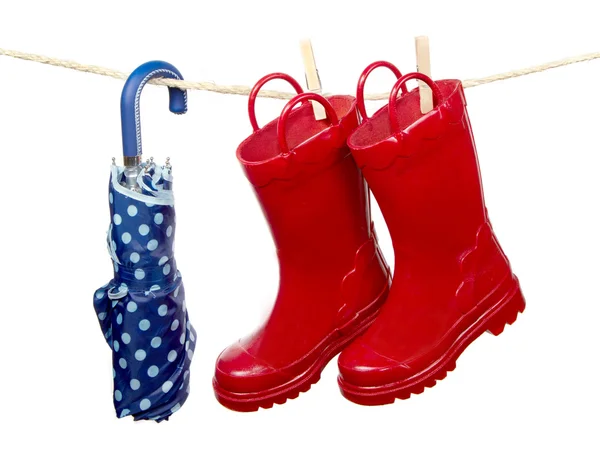 Rain boots and umbrella on a clothes line — Stock Photo, Image