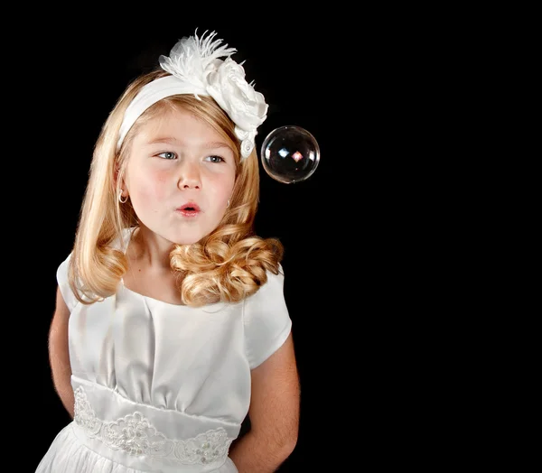 Una chica vestida de blanco soplando una burbuja — Foto de Stock