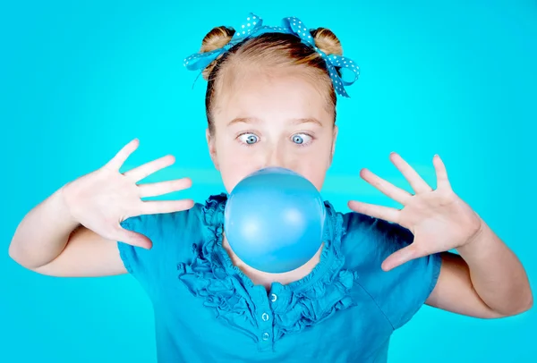 Una chica tonta vestida de azul soplando una burbuja azul —  Fotos de Stock