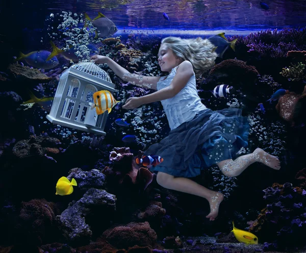 Une fille nageant dans un aquarium tenant une cage à oiseaux — Photo