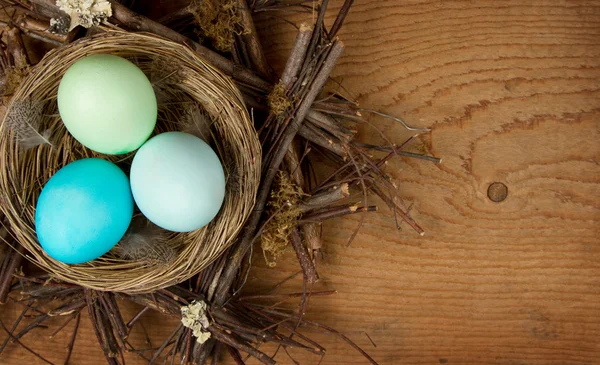 Ovos de Páscoa em um ninho em um fundo de madeira — Fotografia de Stock