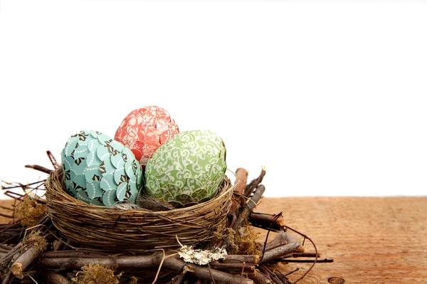 Paper covered easter eggs in a nest on a white background — Stock Photo, Image