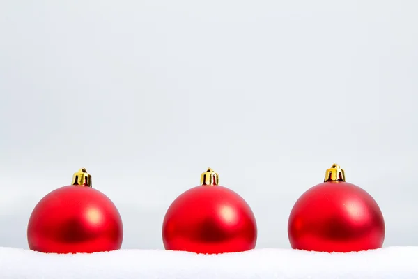 Três ornamentos de Natal vermelho na neve — Fotografia de Stock