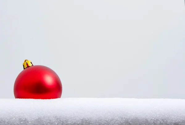 Красный рождественский орнамент в снегу — стоковое фото