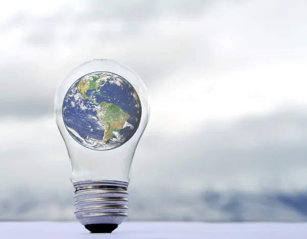 stock image An earth in a lightbulb on a natural background