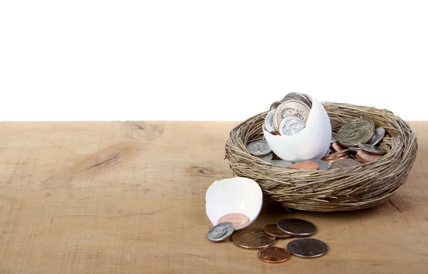 Um ovo aberto rachado com moedas derramando — Fotografia de Stock