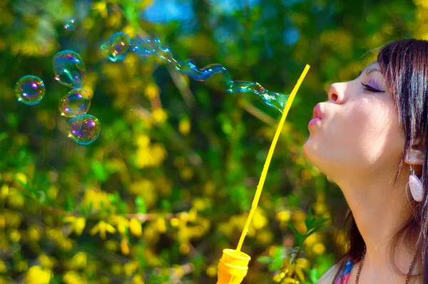 Брюнетка дівчина дме мильні бульбашки на вітрі — стокове фото