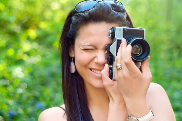 Молодая брюнетка пытается сфотографироваться со старой камерой — стоковое фото