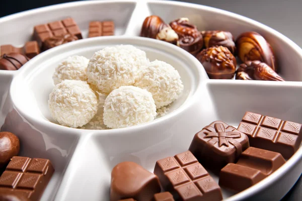 Little pieces of dark chocolate on white plate — Stock Photo, Image