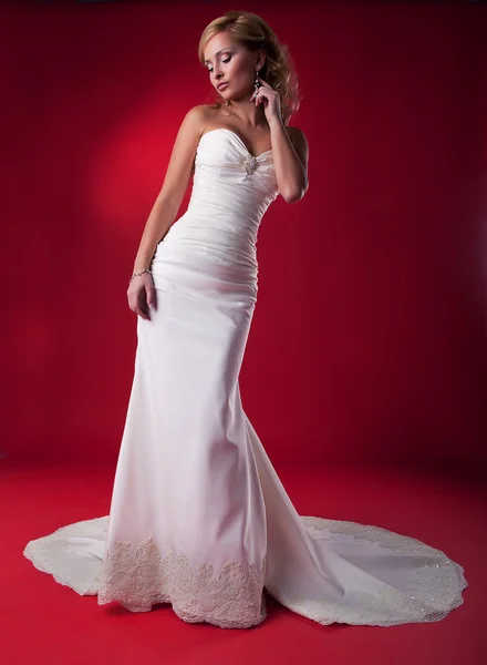 Bonita novia en vestido largo de boda blanco sobre fondo rojo posando —  Fotos de Stock