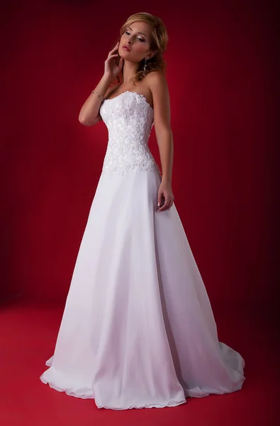 Noiva loira na moda em vestido de noiva branco longo posando no pódio — Fotografia de Stock