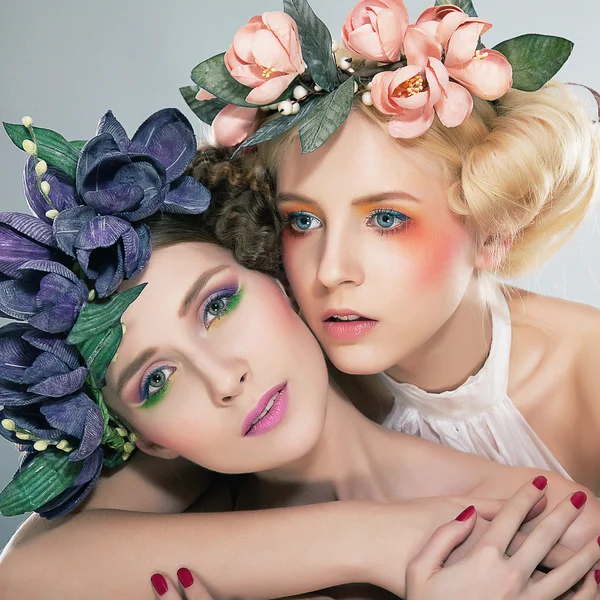 Twee mooie meisjes blond en brunette in gekleurde kransen knuffelen — Stockfoto