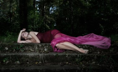 Nocturnal scene in park with lying pretty nymph in crimson dress clipart