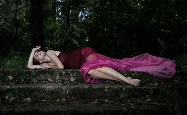Nocturnal scene in park with lying pretty nymph in crimson dress — Stock Photo, Image