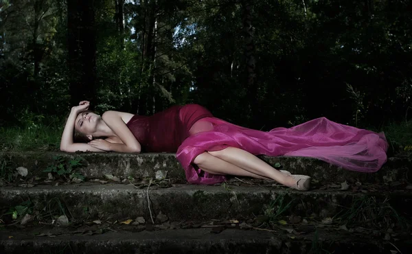 Escena nocturna en el parque con la mentira bonita ninfa en vestido carmesí — Foto de Stock