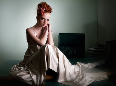 Red head freckled lady in ivory fashion dress on office desk